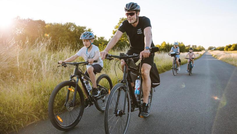 Cycling family on long, straight country road on Kær Halvø