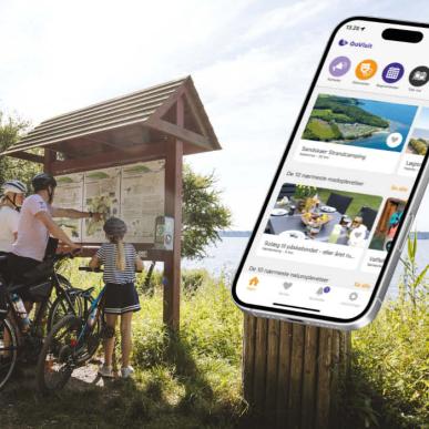En familie står og kigger på et kort, og der er en mockup af en mobil med en åben app.