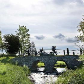 Cyclists on the boulder bridge crossing Hærvejen